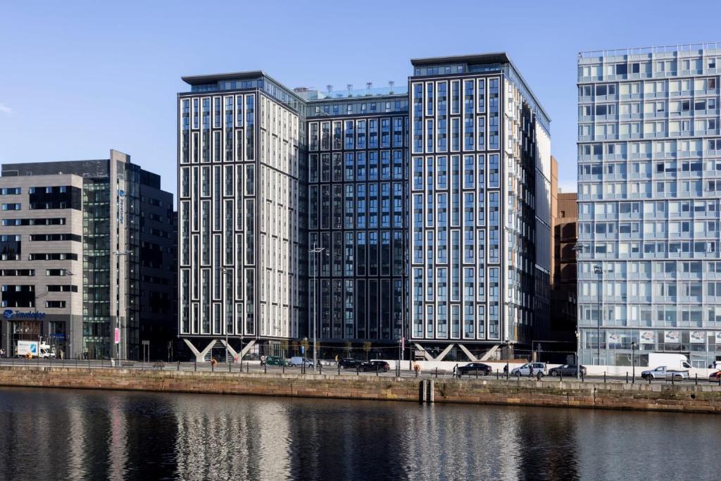 three tall buildings in a city next to a river at Premium Apartments at Copper House in Liverpool City Centre in Liverpool