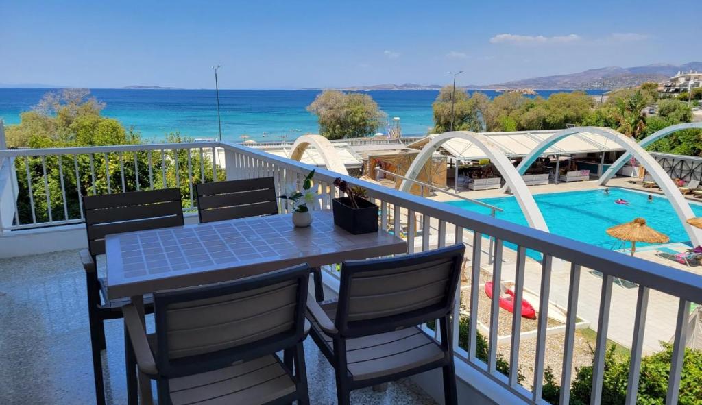 una mesa y sillas en un balcón con piscina en VISTA MARE beachfront apartment., en Saronida