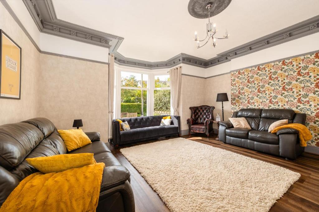 sala de estar con sofás de cuero y alfombra en The Tall House - Sleeps 16, en Keswick