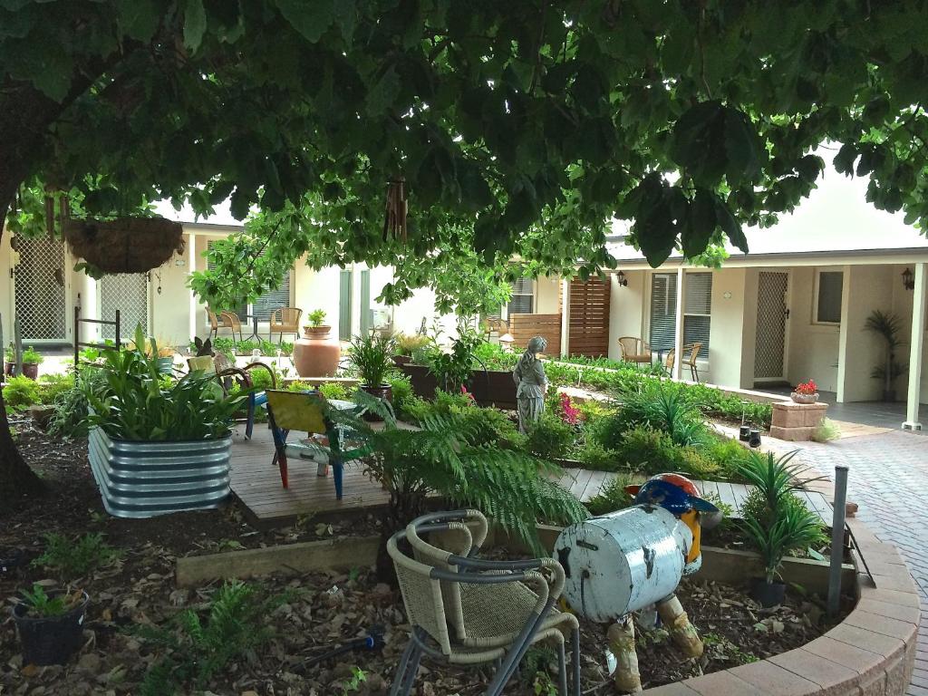 un patio trasero con mesa, sillas y plantas en Hahndorf Oak Tree Cottages, en Hahndorf