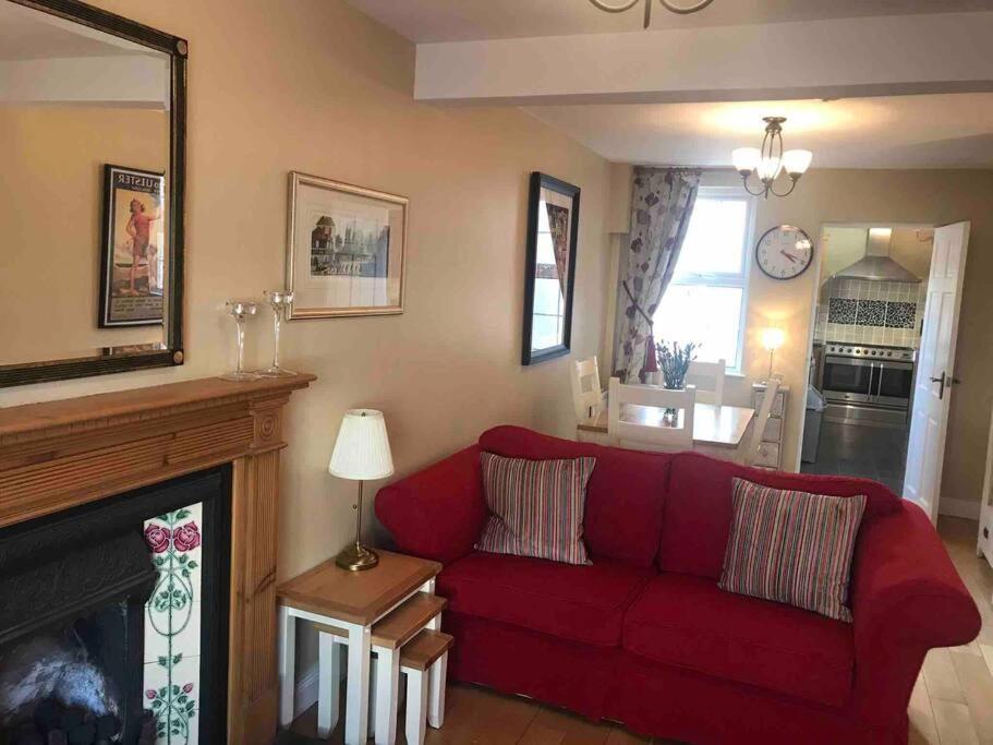 uma sala de estar com um sofá vermelho e uma lareira em Downshire Cottage: Cosy home in Holywood Centre em Holywood