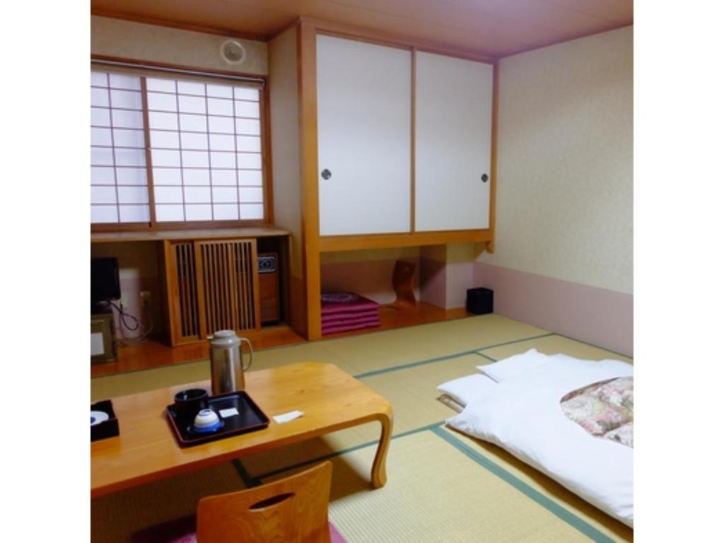 a room with a table and a bed and cabinets at Daikokuya Ryokan - Vacation STAY 53583v in Hakodate