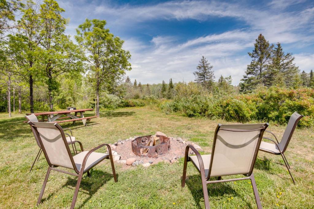 two chairs and a fire pit in a yard at Pet-Friendly Iron River Cabin with Fire Pit! in Iron River