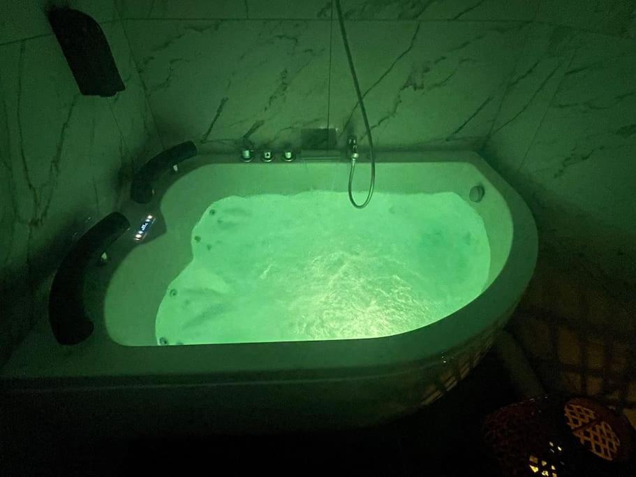 a bath tub filled with green water in a bathroom at L’escapade Balnéo, Centre ville in Sens