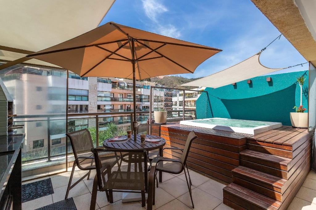a patio with a table and chairs and an umbrella at Jacuzzi Privativa Cobertura no coração de Itaipava in Itaipava