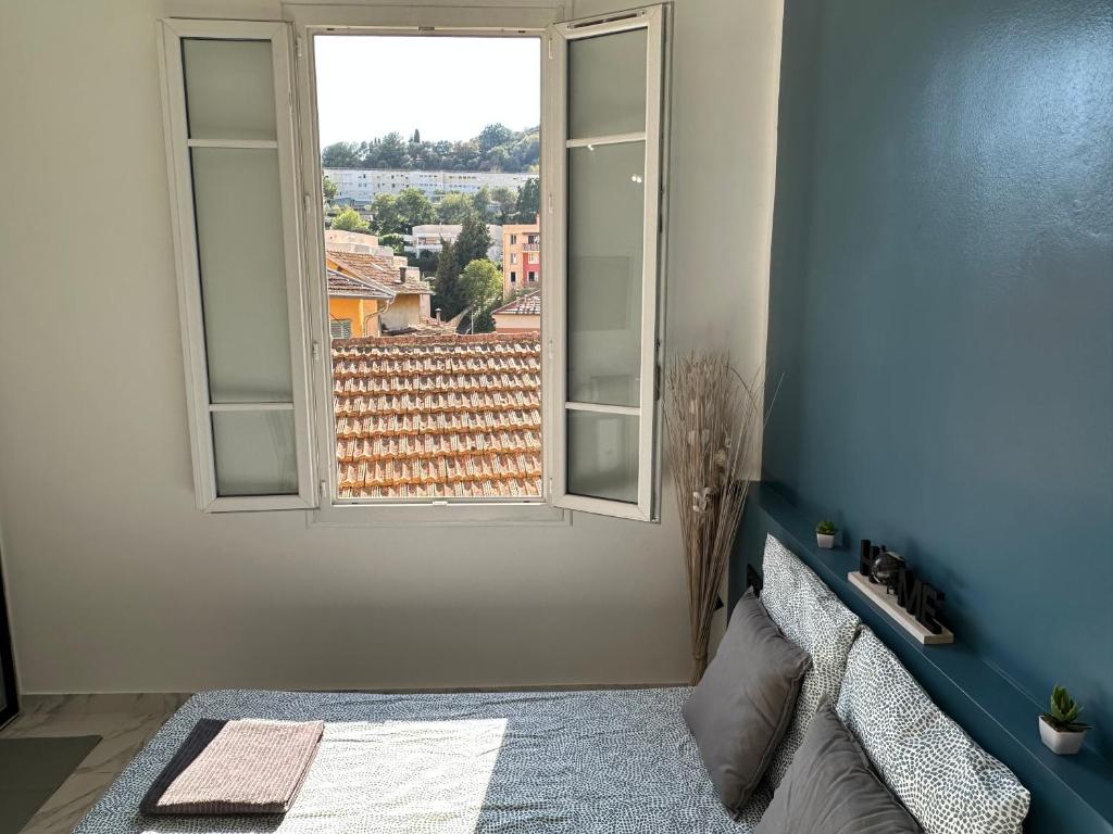 a room with a bed and a window with a view at La maison de Giulia Menton in Menton