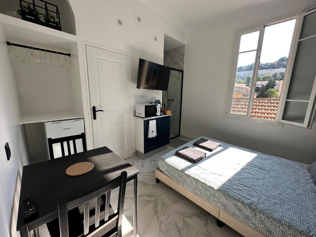 a bedroom with a bed and a table and a window at La maison de Giulia Menton in Menton