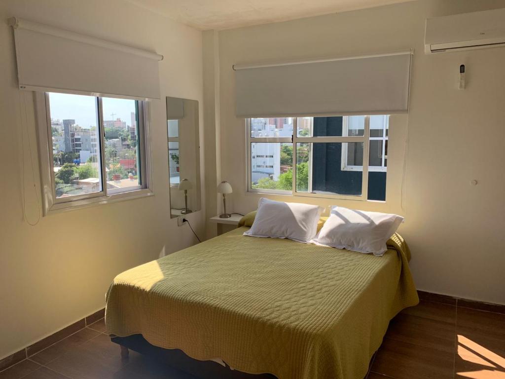 - une chambre avec un lit avec deux oreillers et deux fenêtres dans l'établissement EDIFICIO REY NIÑO, à Posadas