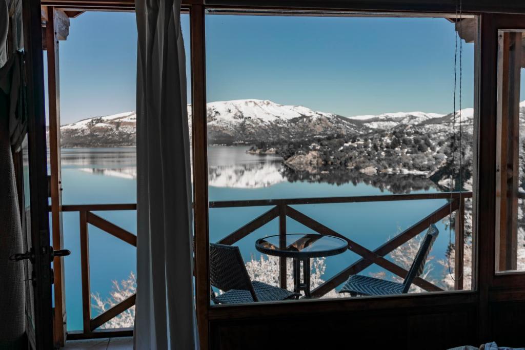 a view of a lake from a room with a window at Complejo Puerto Malén Club de Montaña in Villa Pehuenia