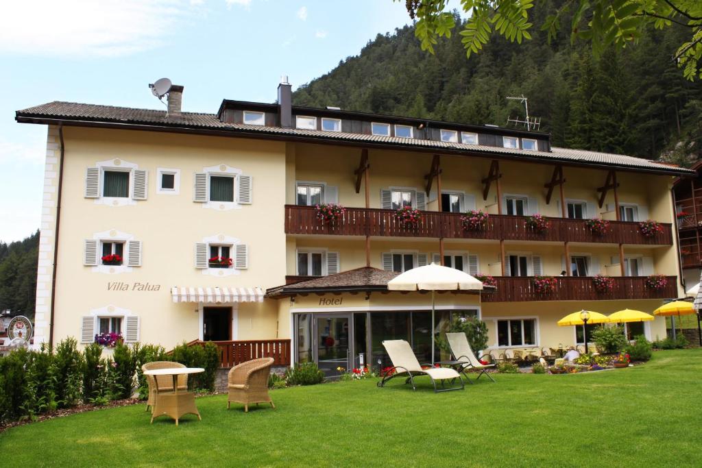 un gran edificio con sillas y sombrillas en un patio en Christeinerhof, en Santa Cristina Valgardena