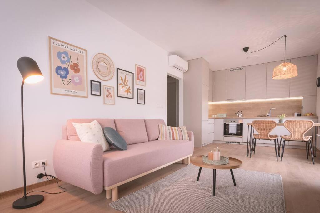 Una sala de estar con un sofá rosa y una mesa. en Nový štýlový byt, blízko letiska, en Bratislava