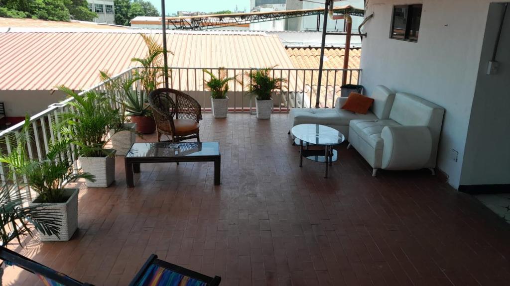 een balkon met een bank, tafels en potplanten bij HOTEL LA CORDIALIDAD in Barranquilla