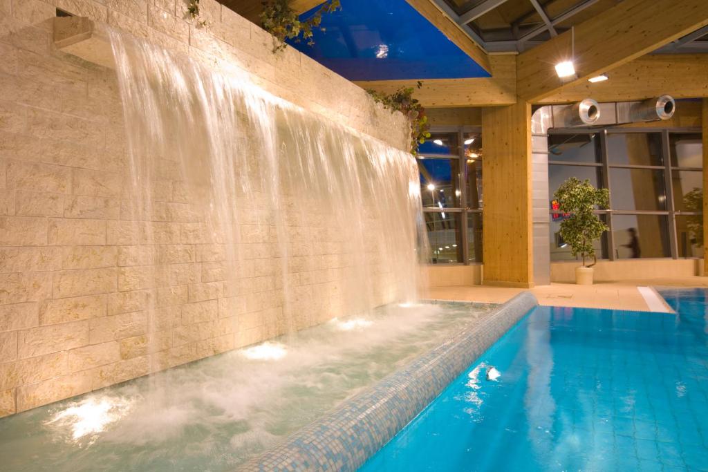 a swimming pool with a waterfall in a building at Alga Baltic Resort in Świnoujście