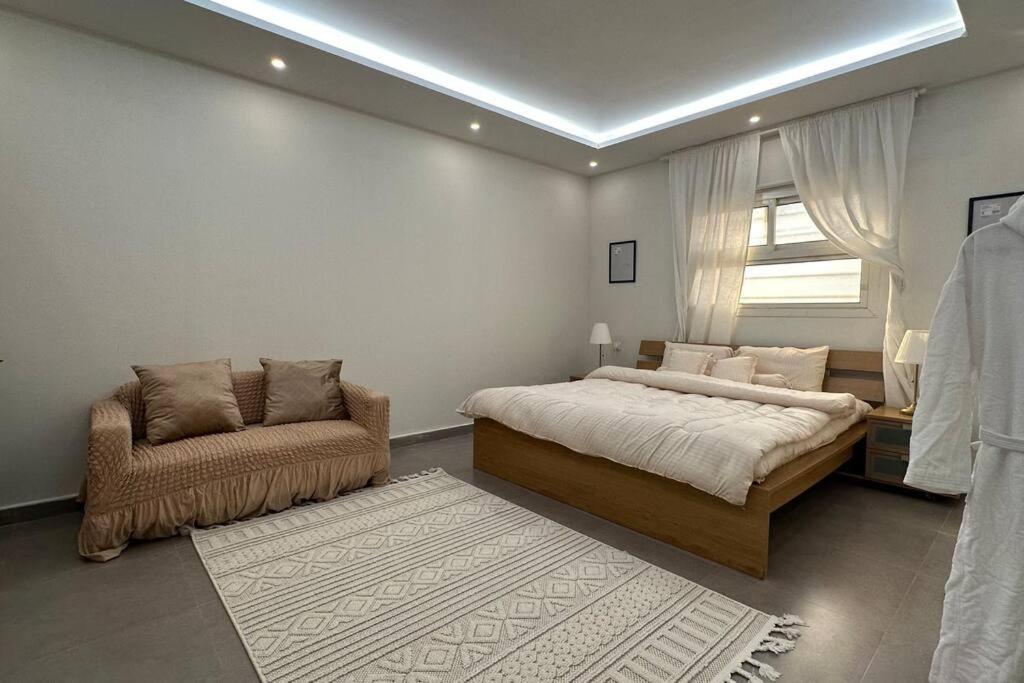 a bedroom with a bed and a chair and a window at Modern cozy apartment in Riyadh