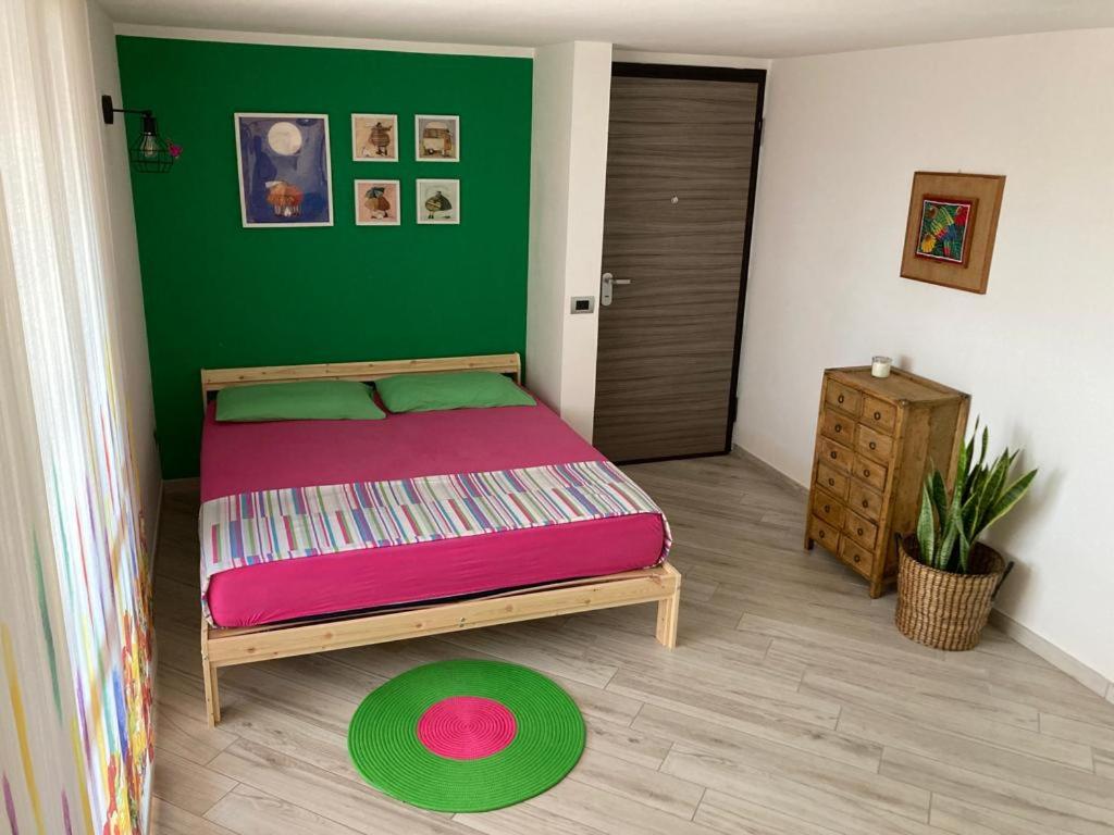 1 dormitorio con cama y pared verde en La casita, en Civitavecchia