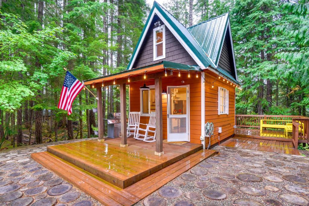 uma pequena casa com um alpendre e uma bandeira americana em Adorable A-Frame Cabin, Steps to Lake Cushman! em Hoodsport