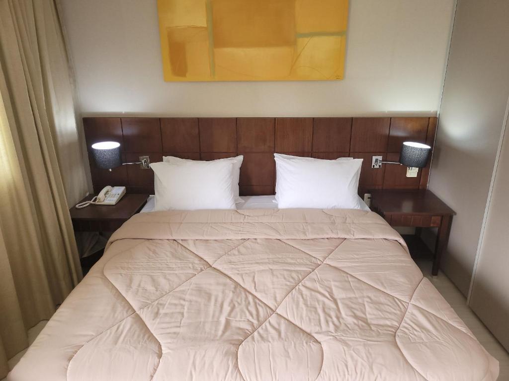 a bedroom with a large bed with two night stands at Flat Super Luxo Verbo Divino in Sao Paulo