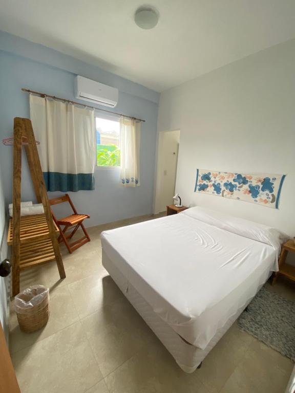 Un dormitorio con una gran cama blanca y una escalera en Caeté Suítes, en Ubatuba