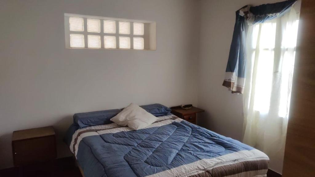 sypialnia z łóżkiem z niebieską kołdrą i oknem w obiekcie HOSTAL DE PARQUE w mieście El Carmen