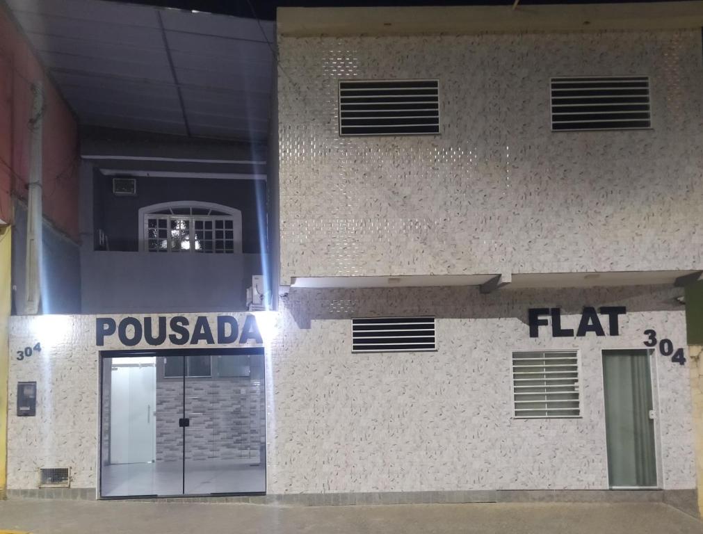 a building with a sign that reads poulada and a fl hit at Pousada Quarto com tv,ar,frigobar,wifi e garagem in Aparecida