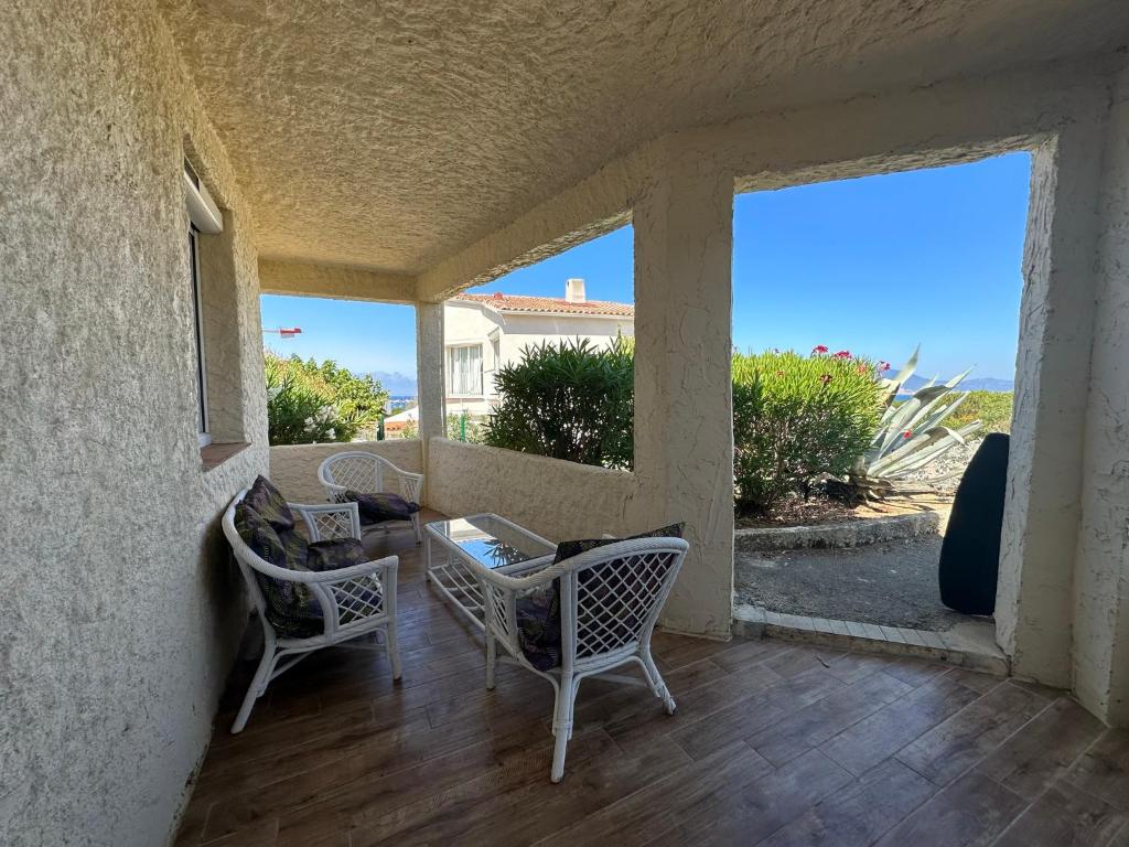 - une terrasse couverte avec 2 chaises, une table et des fenêtres dans l'établissement Bas de villa Climatisé et wifi 2 chambre pour 4 personnes et petite vue mer, à Pietrosella