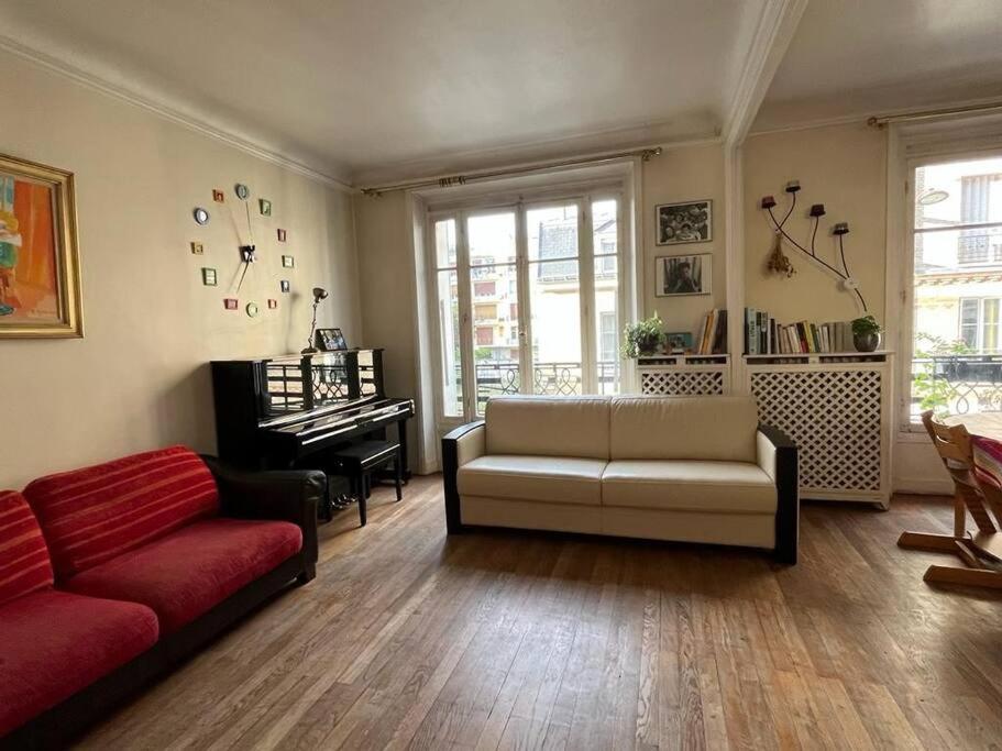 a living room with a couch and a piano at Le grand calme à deux pas de Paris in Neuilly-sur-Seine