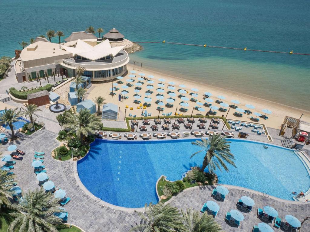 an aerial view of a resort with a pool and a beach at Hilton Doha in Doha