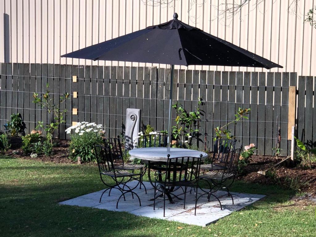 a table and chairs with an umbrella in a yard at Waikaraka Beach, spacious & very comfortable in Whangarei Heads
