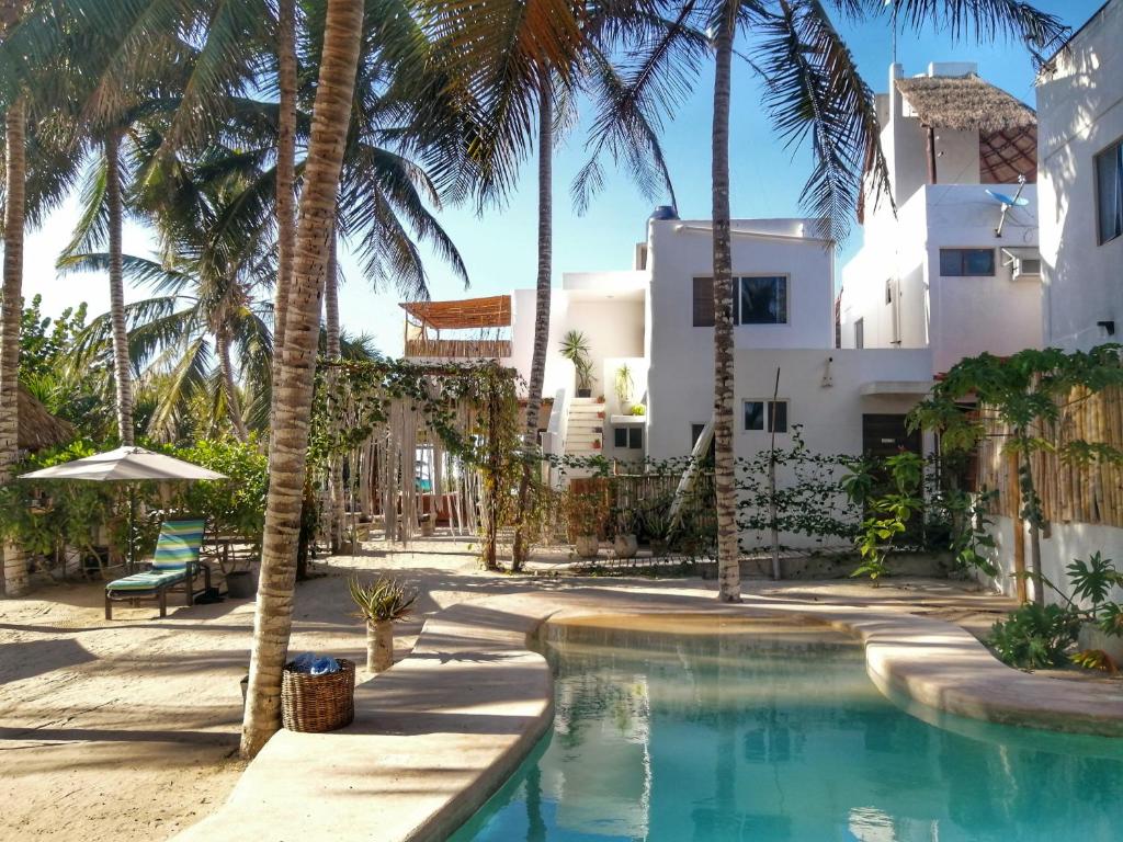 une piscine en face d'une maison avec des palmiers dans l'établissement Hotel Boutique Can Cocal El Cuyo, à El Cuyo