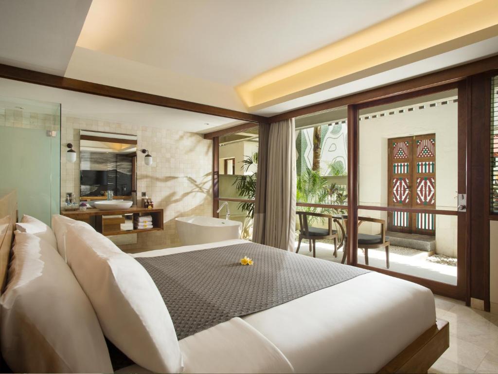 a bedroom with a large bed and a balcony at Amnaya Resort Kuta in Kuta