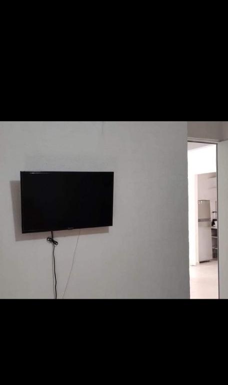 uma televisão de ecrã plano pendurada numa parede branca em Departamento vacacional em Playa del Carmen