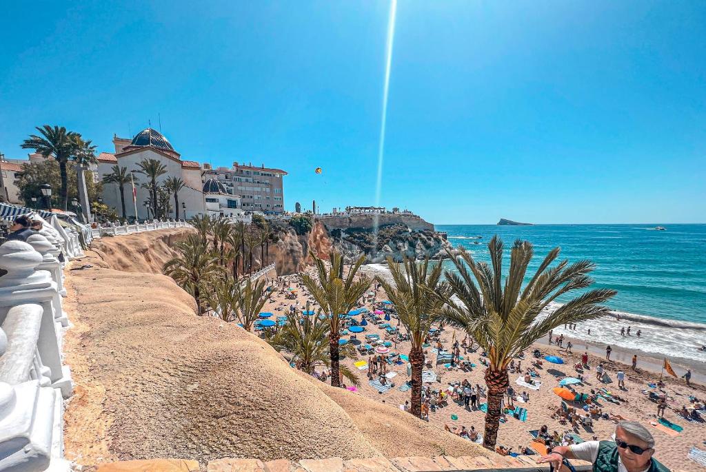 a beach with palm trees and a crowd of people at Fantástico piso en Benidorm in Benidorm