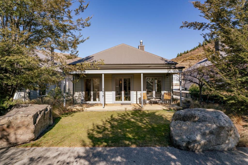 a house with a large rock in the yard at Gold Rush Chalet - Cardrona Holiday Home in Cardrona