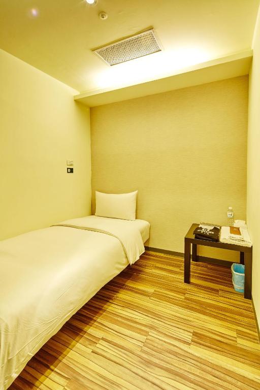 a room with two beds and a table with a bed sidx sidx sidx at Single inn- KAOHSIUNG LINSEN in Kaohsiung