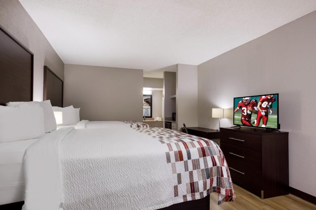 a hotel room with a bed and a flat screen tv at Red Roof Inn & Suites Statesboro - University in Statesboro