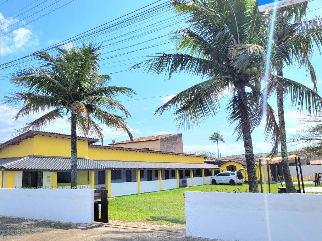 un edificio giallo con palme di fronte di Itamiaru Beach Apartamentos a Ilha Comprida