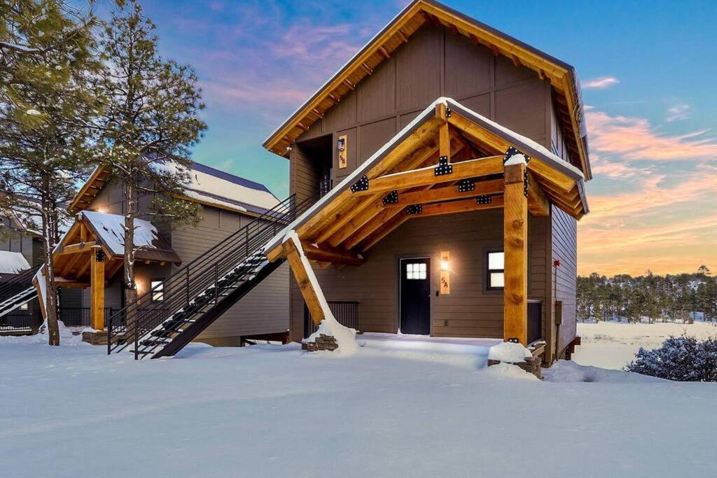 a log cabin in the snow with a wooden staircase at Scenic Villa at Meadow View in Show Low