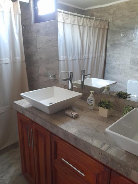 ein Badezimmer mit einem großen weißen Waschbecken und einem Spiegel in der Unterkunft Cabañas Edna in Tinogasta