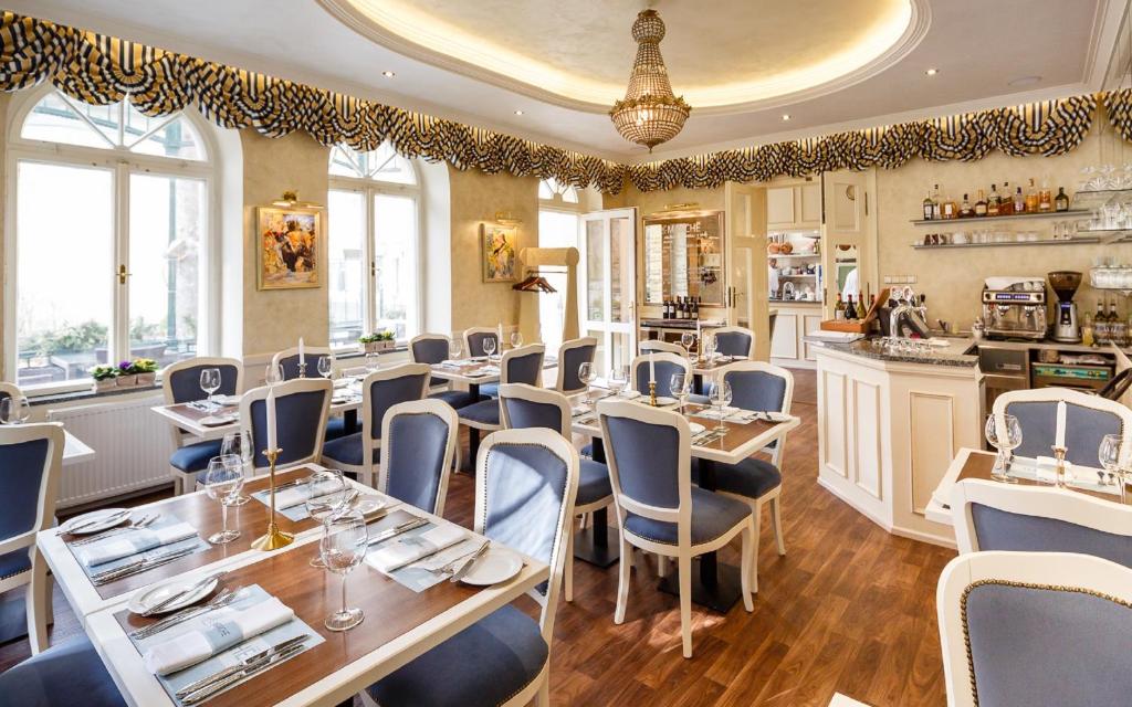 restauracja ze stołami i krzesłami w pokoju w obiekcie Villa Basileia Riverside w Karlowych Warach