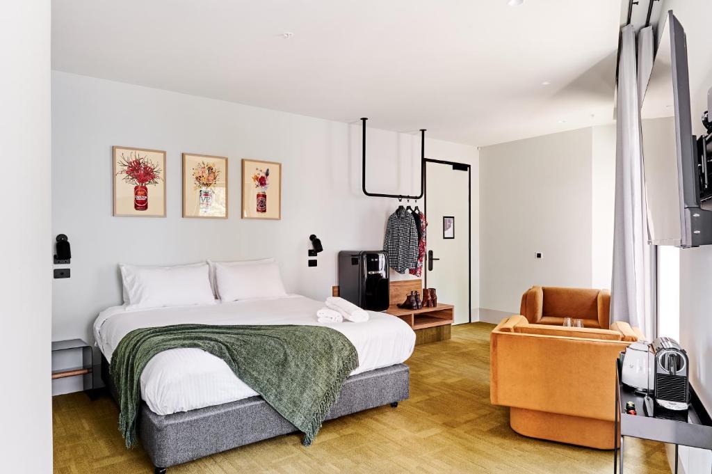 a white bedroom with a bed and a chair at Central Club Hotel - North Melbourne in Melbourne