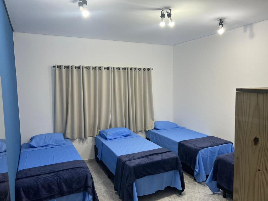 a hospital room with three beds and a television at HOSTEL CAMINHO DA FE in Aparecida