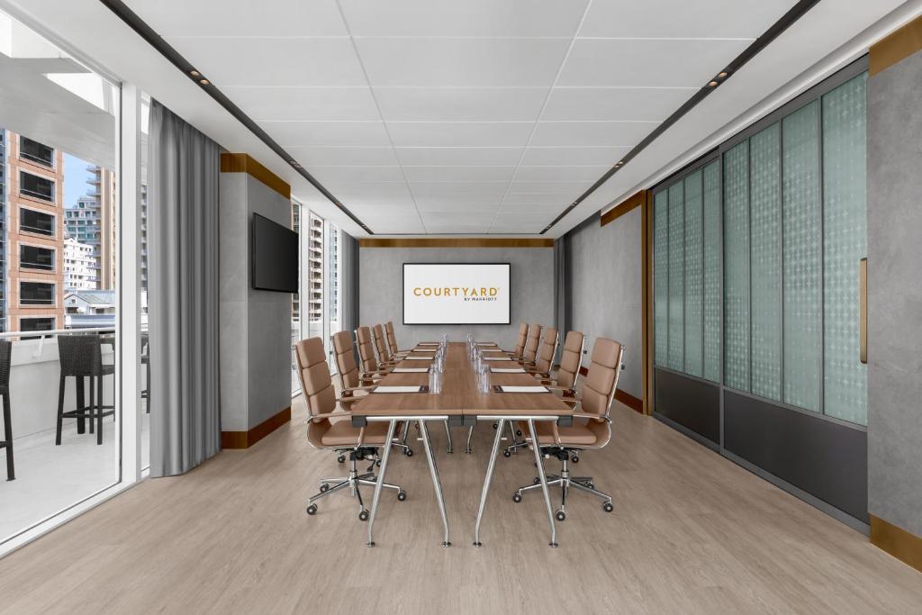 A formal conference room with a long boardroom table and city-facing windows.