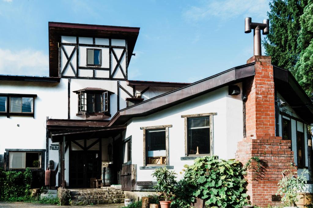 an old white house with a brick chimney at Pension FOLKLORE in Suginosawa