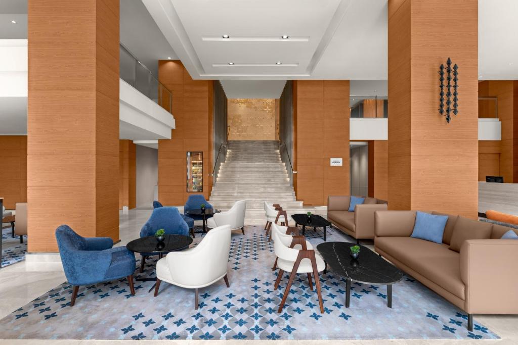 A high-ceilinged lobby lounge with varied seating and a prominent staircase.
