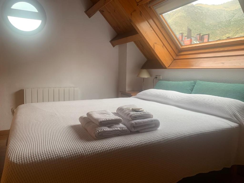 Un dormitorio con dos toallas en una cama con ventana. en Allotjament SV, en Pla de l'Ermita
