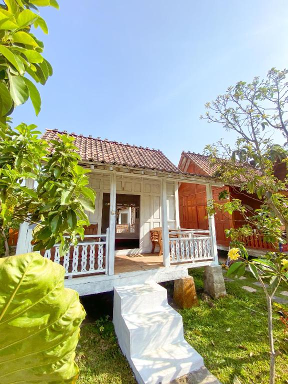 a small house with a porch in a garden at Villa Kamar Tamu Bangunjiwo in Ngingas