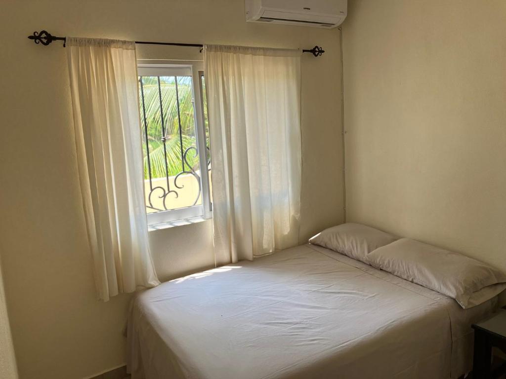 a small bedroom with a bed and a window at Los Amores Apartments B in Pérula