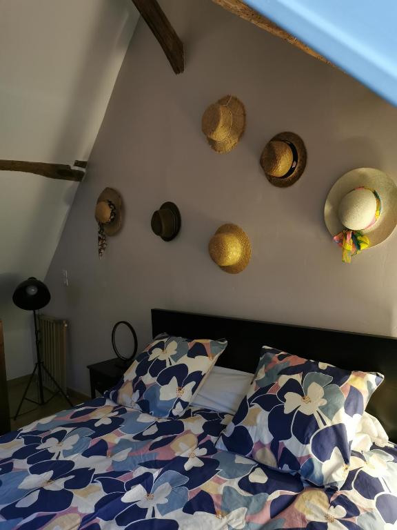 - une chambre avec un lit et quelques chapeaux sur le mur dans l'établissement La Maison d'Yvonne, à La Bouille