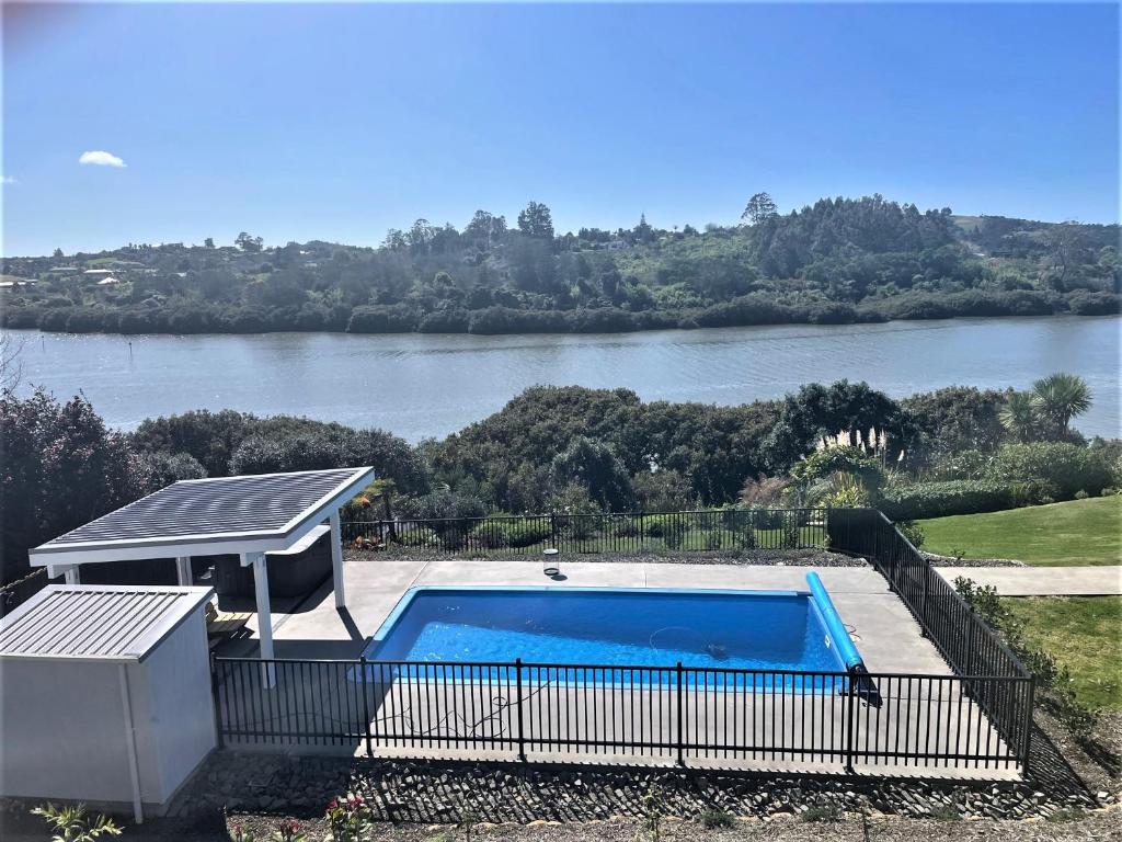a swimming pool with a gazebo next to a river at Pickmere Waters in Kerikeri