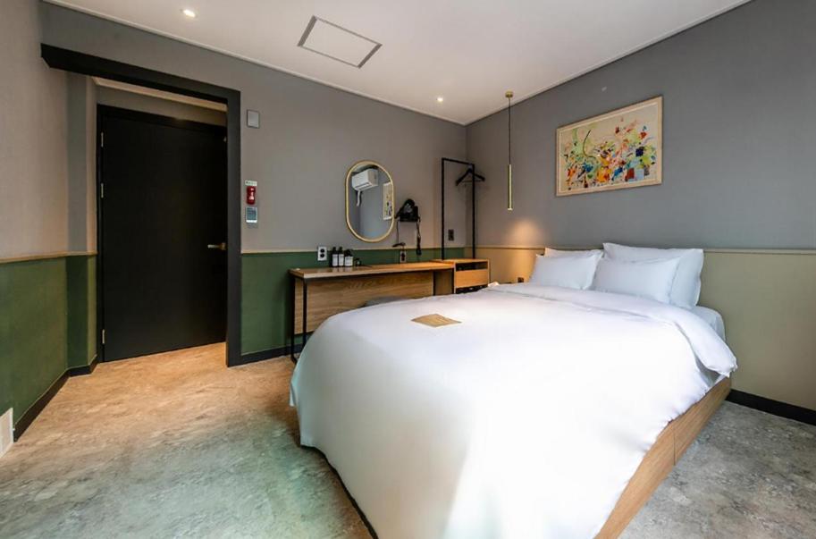 a bedroom with a large white bed and a mirror at Hotel No. 25 Gyeongju bus terminal in Gyeongju